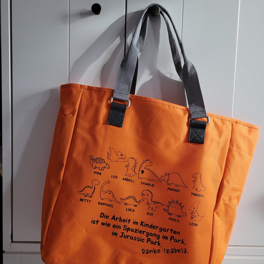 Orange Tasche mit schwarzem Druck von Tieren und einem Text auf Englisch.
